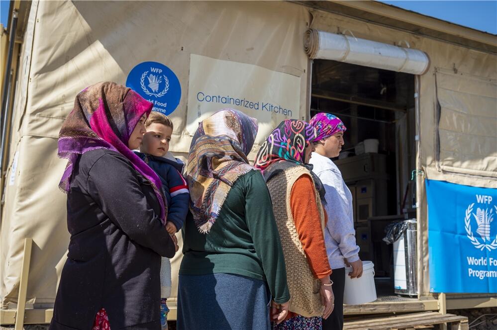 国連WFPの移動式キッチンの前で、温かい食事（豆スープと野菜入りご飯）の受け取りを待つ人々　©WFP/Giulio d'Adamo