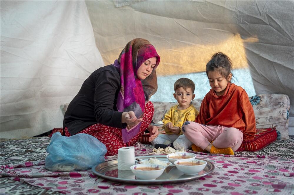 左記写真の最後尾にいた女性・シェイマさん。テントの中で、子どもたちと温かい食事を楽しんでいます　©WFP/Giulio d'Adamo